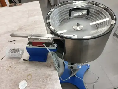 Freestanding stand and sound enclosure for vibratory feeder: ENSO system for noise reduction and stable mounting.